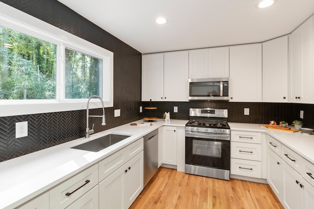 white kitchen cabinets and counters with black appliances and large picture window